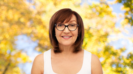 Sticker - beauty, vision and old people concept - portrait of smiling senior woman in glasses over natural autumn background