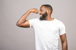Close up portrait of a happy young african american man flexing bicep muscle isolated against grey background.