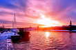 Scenic red purple and violet sunset over countryside river in Europe with old ships having rest at the snowy harbor pier