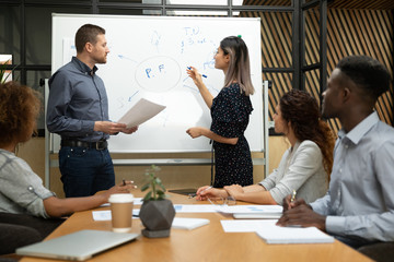 Wall Mural - Diverse asian and caucasian coaches drawing on whiteboard in office