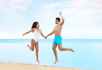 Canvas Print - Happy young couple having fun together on beach near sea