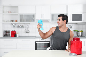 Canvas Print - Young athletic man with protein shake powder in kitchen, space for text