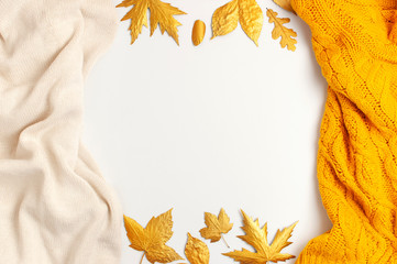 Wall Mural - Flat lay autumn composition. Knitted woolen light beige and yellow orange sweater or plaid, golden dry leaves on white background top view copy space. Autumn, fall concept. Knitted texture