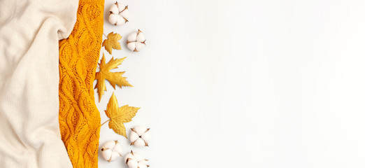 Wall Mural - Flat lay autumn composition. Knitted woolen light beige and yellow orange sweater or plaid, golden dry leaves, cotton flowers on white background top view copy space. Autumn, fall concept