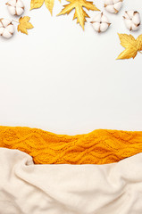 Wall Mural - Flat lay autumn composition. Knitted woolen light beige and yellow orange sweater or plaid, golden dry leaves, cotton flowers on white background top view copy space. Autumn, fall concept