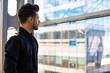 © ZoFot - Young man successful executive director thinking about future his company, standing indoors near window with copy space for promotional content. Pondering male leadership having work break