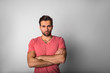 © ZoFot - Portrait of a beautiful bearded brunette hipster guy in pink shirt standing with crossed arms isolated in studio against wall with copy space for advertising text message