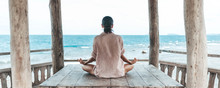 Young Woman Meditating In A Yoga Pose At The Beach