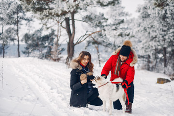  Cute couple in a winter park. Woman palying with a dog. Lady in a black jacket