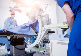 Process of trauma surgery operation. Group of surgeons in operating room with surgery x-ray equipment.