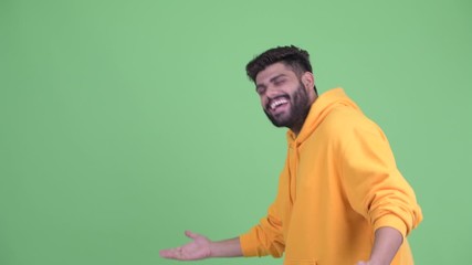 Wall Mural - Happy young overweight bearded Indian man touching something and dancing