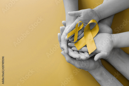 Fotomural adult and children hands holding yellow gold ribbon, Sarcoma Awareness, Bone can