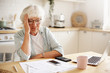 © shurkin_son - Sad frustrated senior woman pensioner having depressed look, holding hand on her face, calculating family budget, sitting at kitchen counter with laptop, papers, coffee, calculator and cell phone
