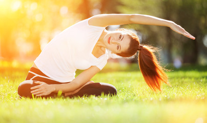 Wall Mural - Yoga outdoor. Happy woman doing yoga exercises, meditate in the park. Yoga meditation in nature. Concept of healthy lifestyle and relaxation. Pretty woman practicing yoga on the grass