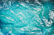 Abstract Artistic Background - Decorative Texture Wrinkles Of Cellophane On Dark Blue Turquoise Art Paper.