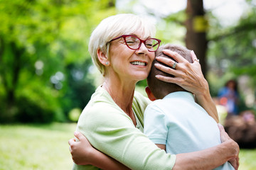 Wall Mural - Happy grandma with grandson embracing in a park outdoors