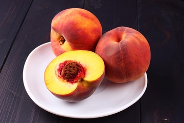 Poster - Peach in a plate on a dark wooden background