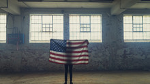 Young Man Holding An American Flag Inside An Empty Warehouse