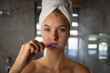 © Wavebreak Media - Young blonde woman brushing her teeth with her hair wrapped in a towel