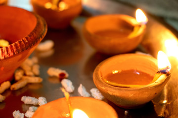 Wall Mural - Macro shots of diyas being lit by hand or candle for the hindu religious festival of Diwali. These colorful earthern pots hold oil and a cotton wick to light