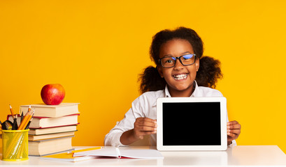 African American Schoolgirl Showing Tablet Screen Sitting At Desk