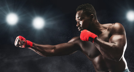 Wall Mural - Side view of professional black man fighting on boxing arena