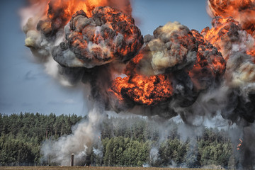 Intense explosion with fire and black smoke and sky in the background