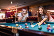 © RomanR - Friends playing billiard aiming on ball in pub