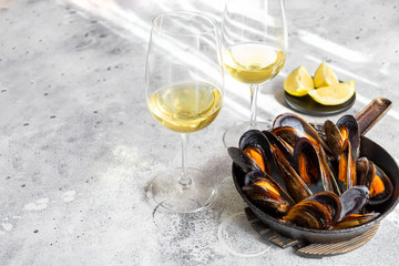 Steamed mussels in frying pan with wine on cement background. Popular  Mediterranean seafood dish background.