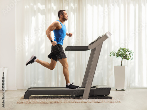 Cuadros en Lienzo Young man running on a treadmill at home