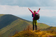 © Андрей Репетий - Young woman hiker standing on the top of mountain with raised hands feeling seccess and freedom