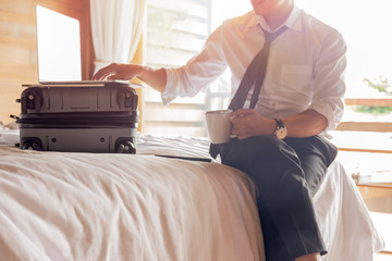 Businessman work on laptop while sitting on hotel bed during business trip.