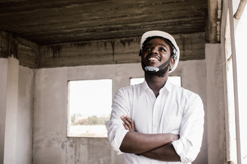 Wall Mural - African construction engineer smiling while wearing helmet.