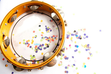 Tambourine, with chopped, colorful confetti, used in carnival.Solk party of samba.Instrument used in street blocks, parade of samba school.White background. From above.Space for your text.