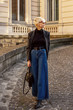 © Victoria Fox - Street style, autumn, fall, winter fashion concept: fashionable woman wearing  luxury grey coat, sunglasses, wide leg blue jeans, square toe ankle bots, holding black leather bag, walking in street