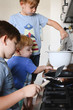 © Westend61 - Three brothers cooking pancakes in the kitchen
