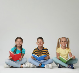 Wall Mural - Little children reading books on grey background