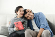 © nuiiko - Happy Asian man giving gift box to his mother for Mother's Day celebration.