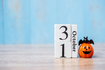 Happy Halloween day with 31 October calendar wood, jack o lantern pumpkin and bat decor with funny face on table background with copy space. Autumn season, Holiday and Trick and Treat concept