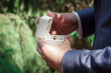 Fototapeta  - Will you be my woman wife?  Wedding ring in a special box, holds in the hands of the groom. Man in a suit shows a ring. The groom has a beautiful casket with wedding rings in her hands. Wedding.