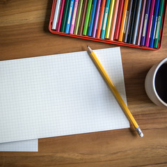 Wall Mural - open graph pad with pencil, color pencils and a cup of coffee on a wooden desk, directly above. copy