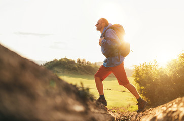 Wall Mural - backpacker traveler in trekking boots jumping over the ditch on mountain dirty path at summertime su