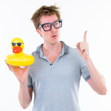 Funny Young Nerd Man With Eyeglasses Holding Inflatable Duck And Pointing Up