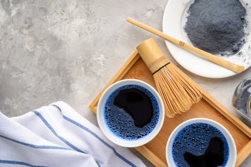 Blue matcha tea in two white cup , wooden tray, bamboo tavan and tasaku, powder on white background