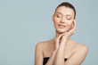 © Alena - woman with clean skin touches her cheeks with her hand. face skin concept on a blue background