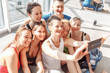© Rithor - Group of positive young people take a selfie on a smartphone after a group of yoga classes in their bright room with a large window. Concept lovers of yoga and pilates