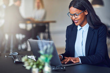 Wall Mural - Smiling young African American businesswoman using a laptop at w