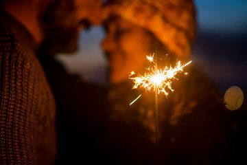 Wall Mural - Romantic couple in love celebrate together the new year start or event party nightlife with fire sparkler - defocused people and close up composition with celebration concept