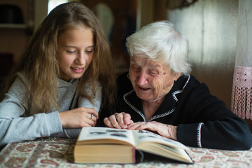 A cute little girl with her grandmother reading a funny book.