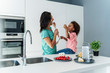 © Westend61 - Mother and daughter cooking in kitchen together playing with wooden spoons